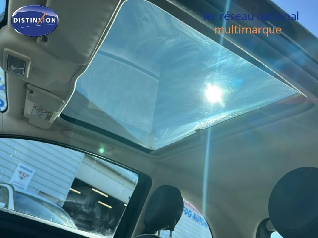 Vue intérieure du toit ouvrant électrique de la Fiat 500 noire, avec lumière du soleil traversant le vitrage panoramique.