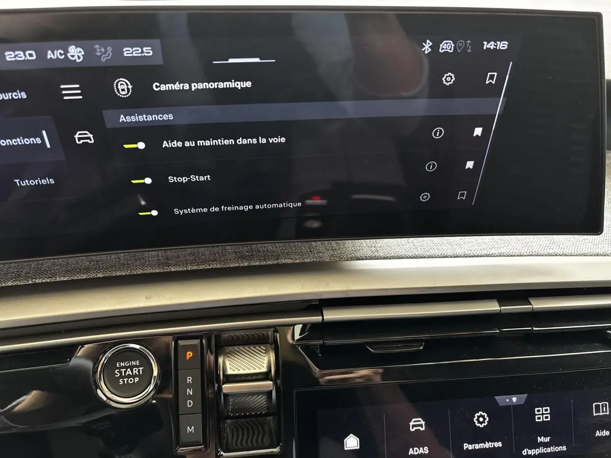 Vue rapprochée de la console centrale du Peugeot 5008 gris clair, avec écran tactile et bouton start/stop visible.