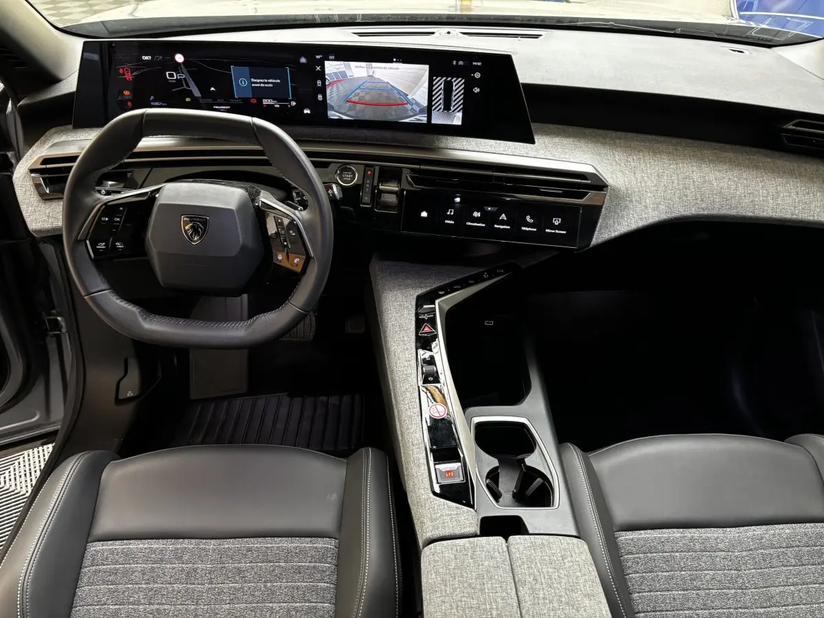 Vue intérieure avant du Peugeot 5008 2025 gris clair, tableau de bord avec écran tactile panoramique et volant multifonctions.