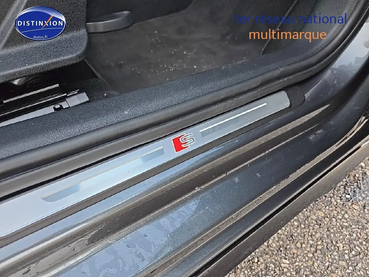 Gros plan sur le seuil de porte avec logo S illuminé de l'Audi A3 Sportback gris Daytona côté gauche.