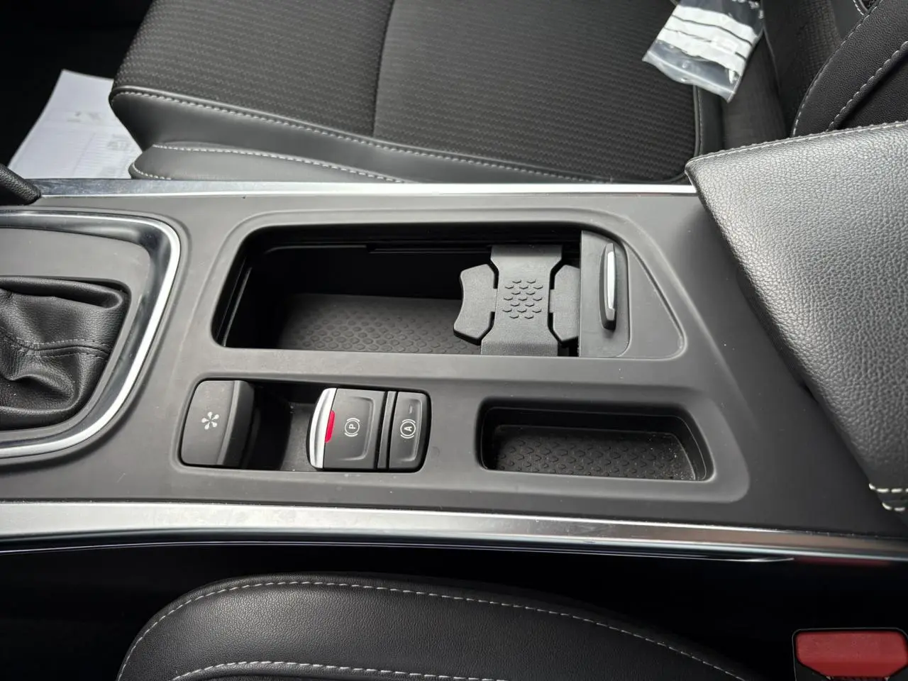 Vue rapprochée de la console centrale noire avec commandes de frein à main électrique et rangement sur Renault Mégane Break 2024.