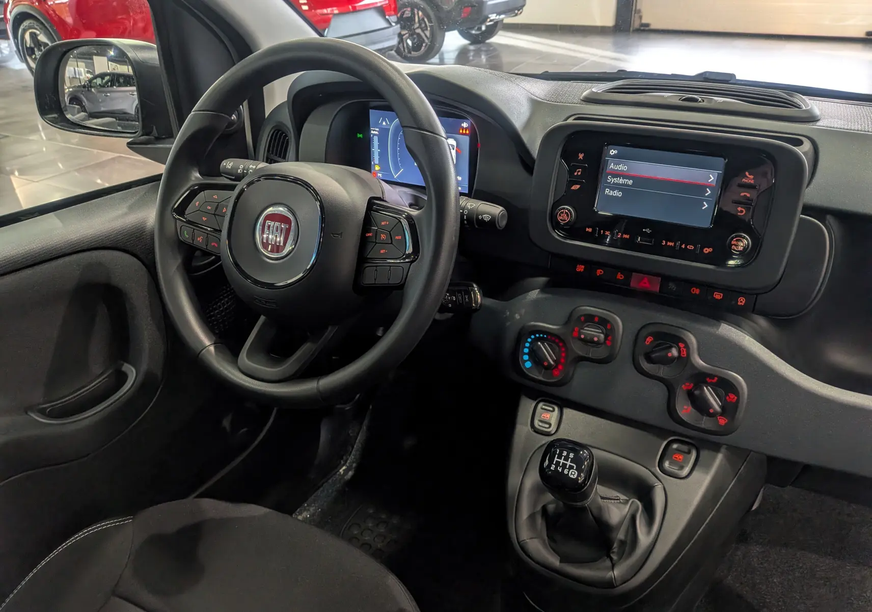 Vue intérieure côté conducteur de la Fiat Panda blanche Gelato 2025, avec volant multifonction et tableau de bord numérique.