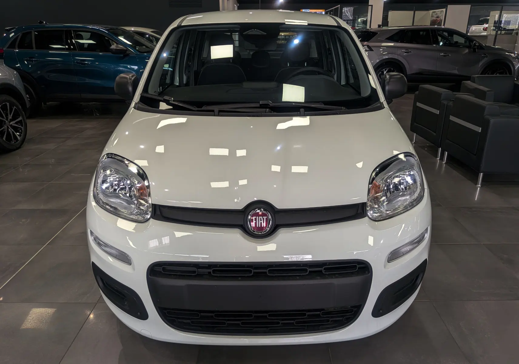 Vue avant d'une Fiat Panda 1.0 70 CH Hybrid City blanche Gelato, avec logo Fiat visible au centre de la calandre.