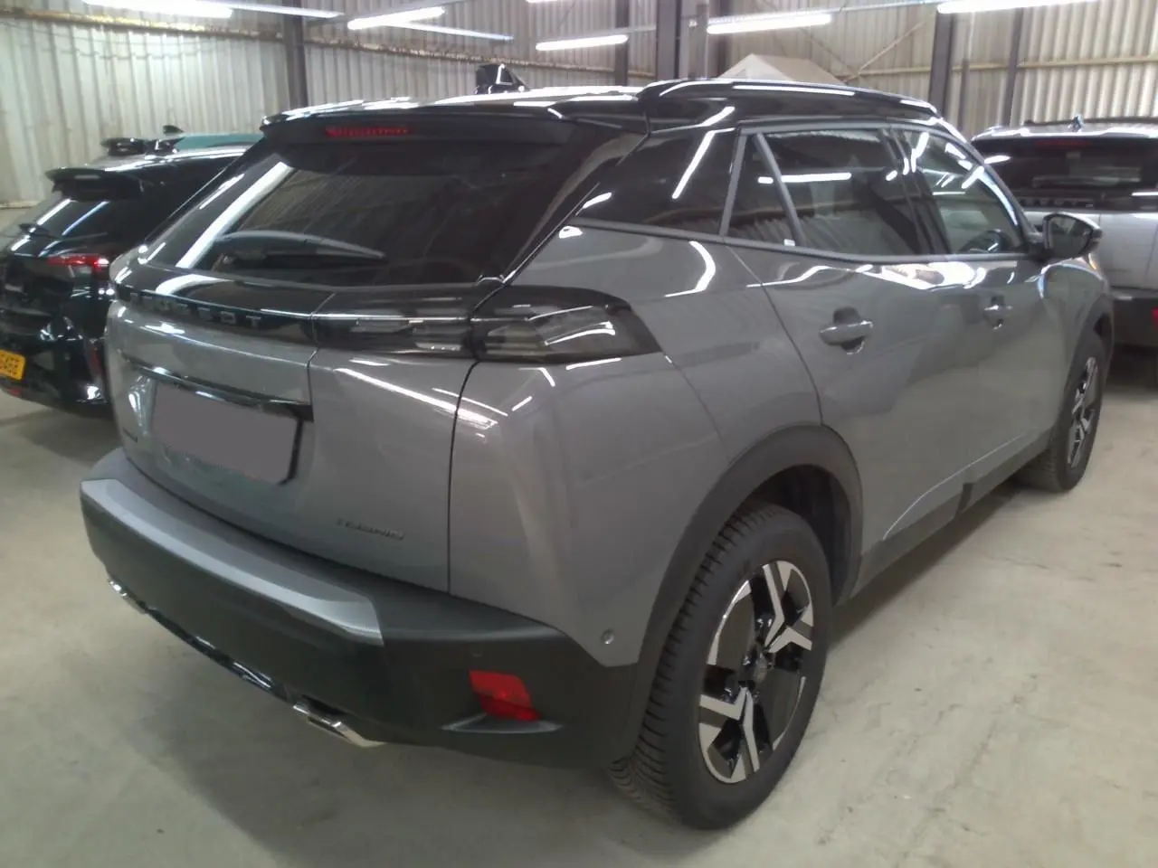 Vue 3/4 arrière droite d'un Peugeot 2008 gris selenium avec barres de toit noires et vitres teintées.
