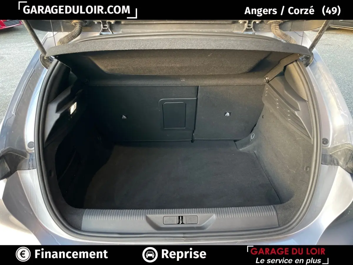 Coffre ouvert d'une Peugeot 308 gris foncé, vue arrière montrant l'espace de chargement propre et spacieux.