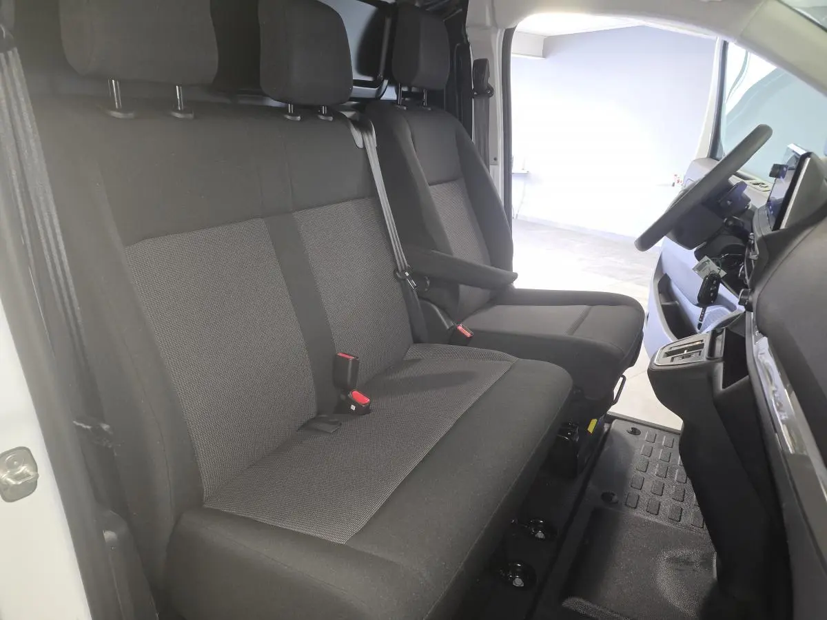 Vue intérieure côté conducteur du poste de conduite et banquette noire du fourgon blanc Opel Vivaro 2025.