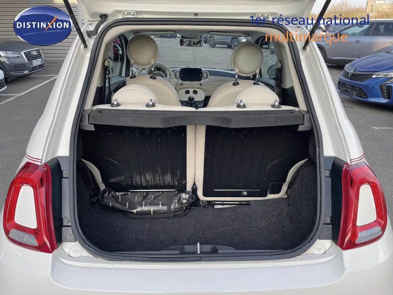 Vue arrière ouverte d'une FIAT 500 blanche 2022, montrant le coffre vide et l'intérieur clair avec sièges en cuir blanc.