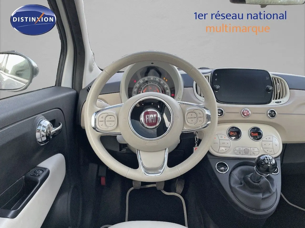 Vue intérieure centrée sur le volant beige et tableau de bord clair de la Fiat 500 blanche 1.0 Hybrid 2022.