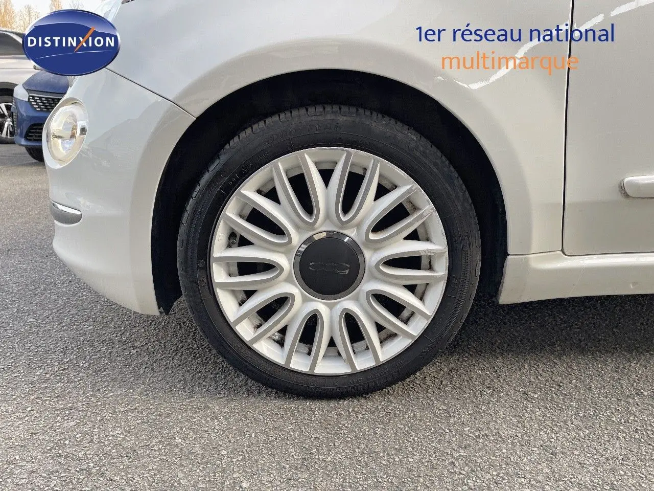 Gros plan sur la roue avant gauche blanche d'une FIAT 500 1.0 HYBRID 70CH DOLCEVITA de 2022, avec jante multibranches.