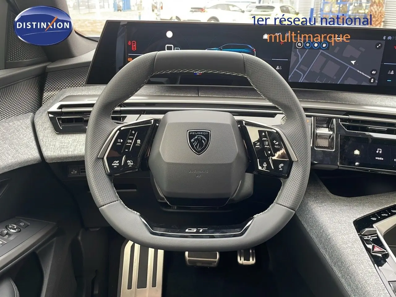 Vue rapprochée du volant GT en cuir gris du Peugeot 5008 Hybrid 2025 avec tableau de bord numérique et écran tactile.