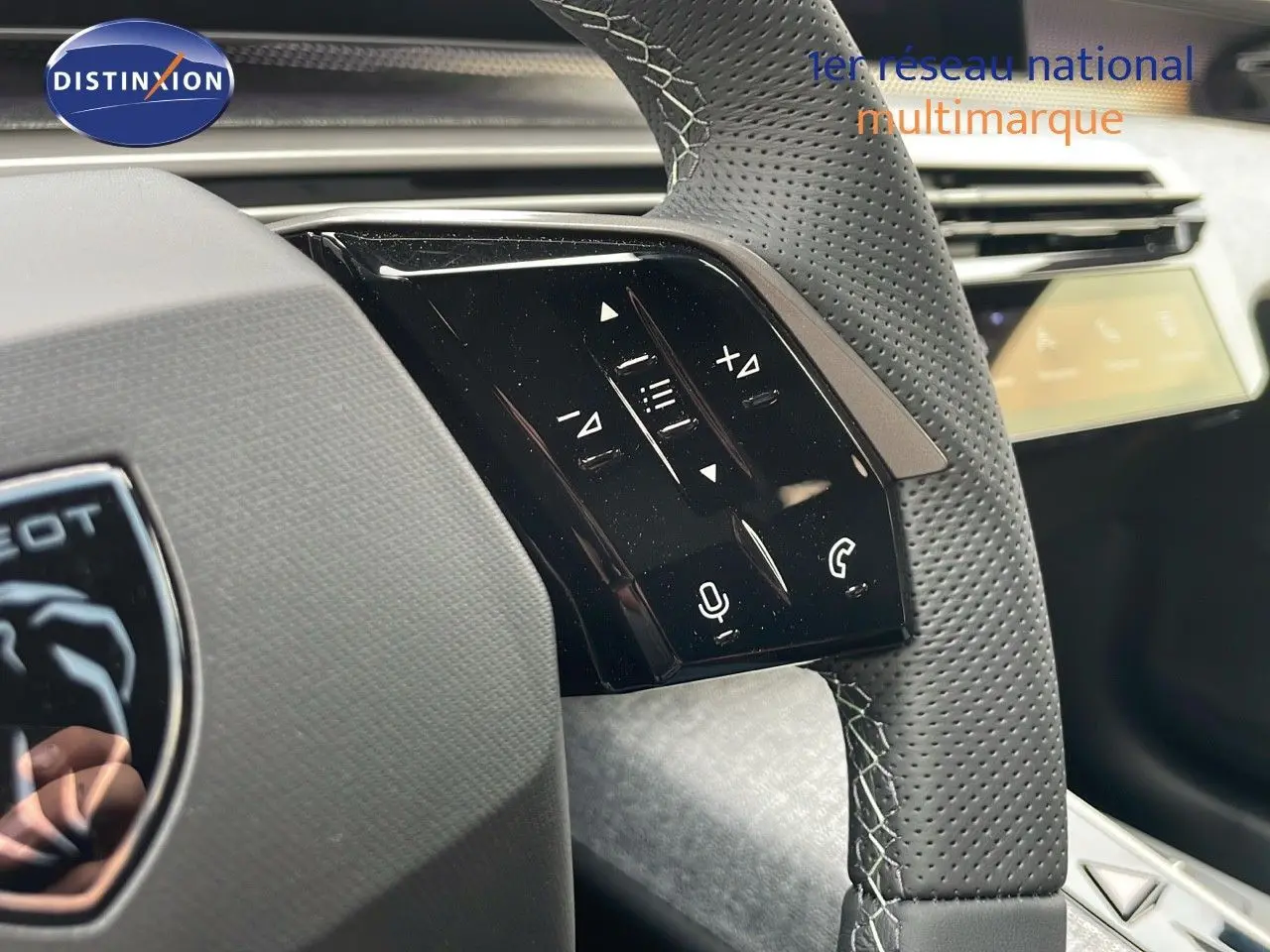 Gros plan sur le volant en cuir perforé gris du Peugeot 5008 Hybrid 136ch GT, avec commandes tactiles intégrées.