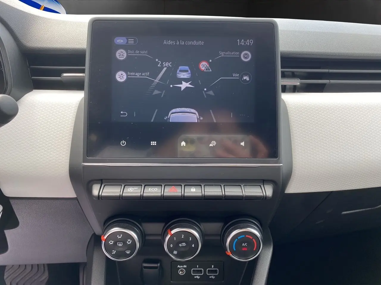 Tableau de bord de Renault Clio V TCE 90 Evolution, écran tactile affichant aides à la conduite, commandes de climatisation visibles.