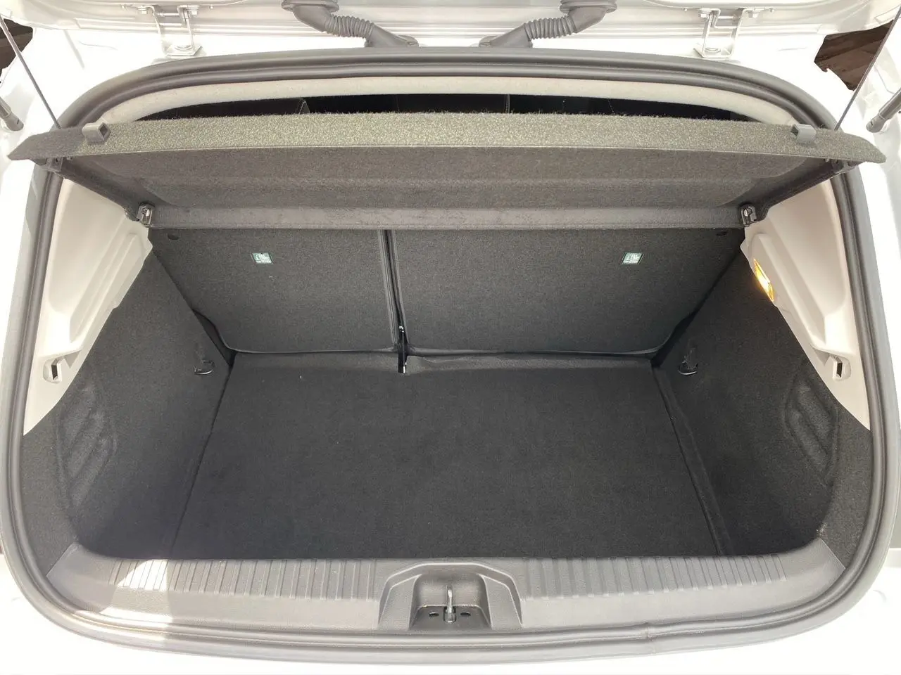 Coffre ouvert d'une Renault Clio V gris Highland, vue de dessus montrant l'espace de chargement vide et la tablette arrière.