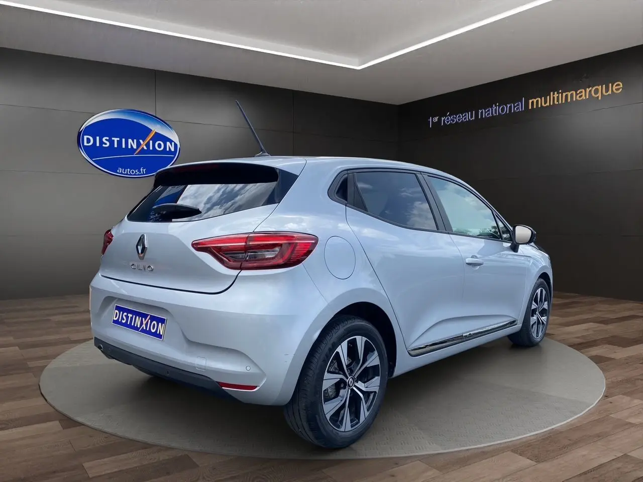 Renault Clio V gris Highland vue 3/4 arrière droit, jantes alliage et vitres teintées en showroom.