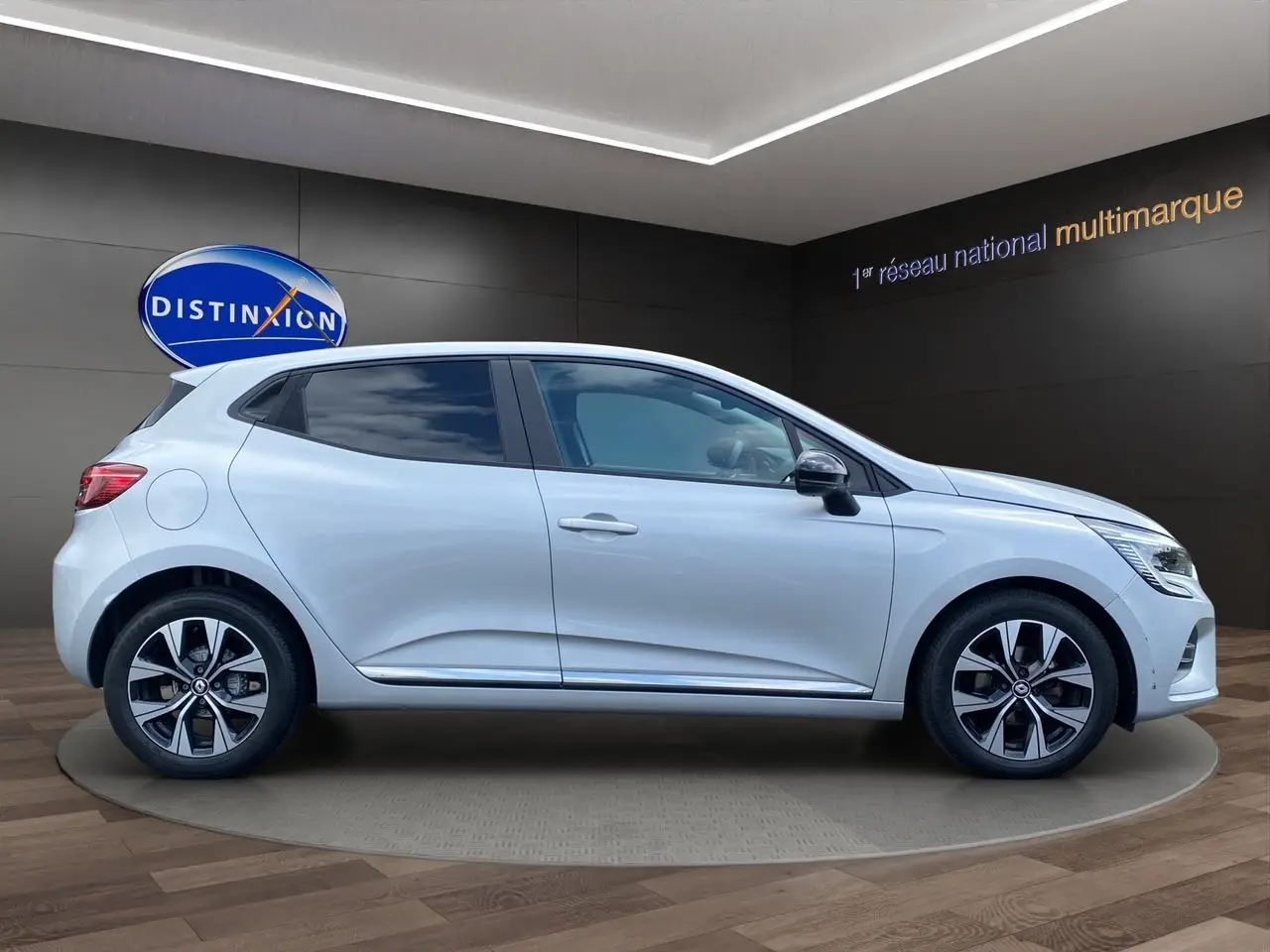 Profil côté droit d'une Renault Clio V gris Highland 2023 avec jantes alliage et vitres teintées en showroom.