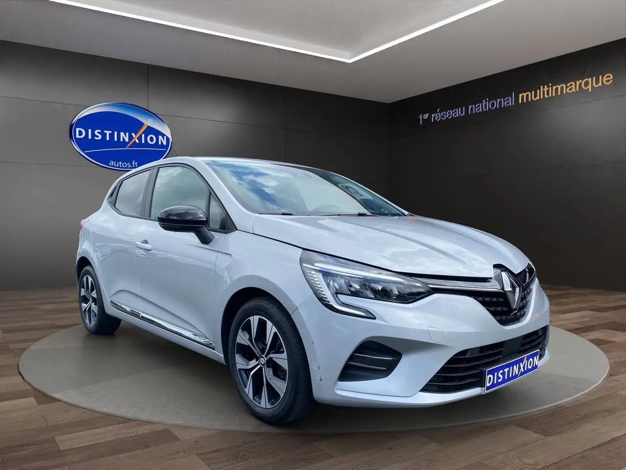 Renault Clio V TCE 90 gris Highland vue 3/4 avant droit avec jantes alliage et feux LED en showroom