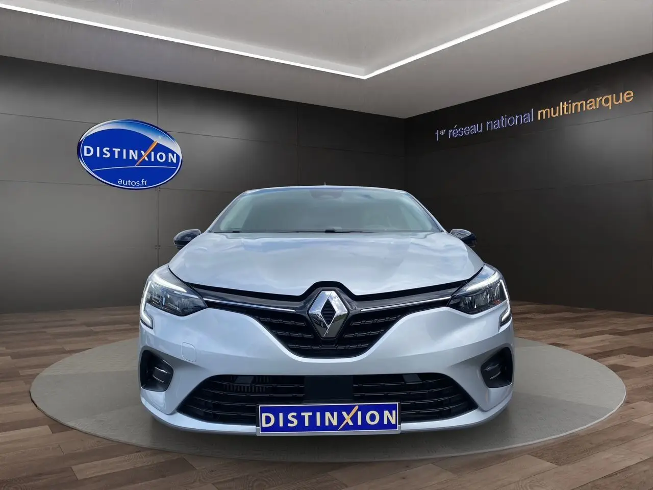 Vue frontale d'une Renault Clio V TCE 90 Evolution gris Highland avec calandre noire et logo Renault bien visible.