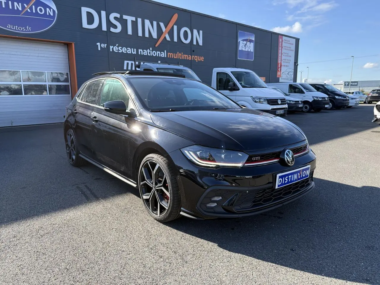 Volkswagen Polo GTI noire en 3/4 avant droit, avec jantes alliage 18 pouces et calandre GTI rouge.
