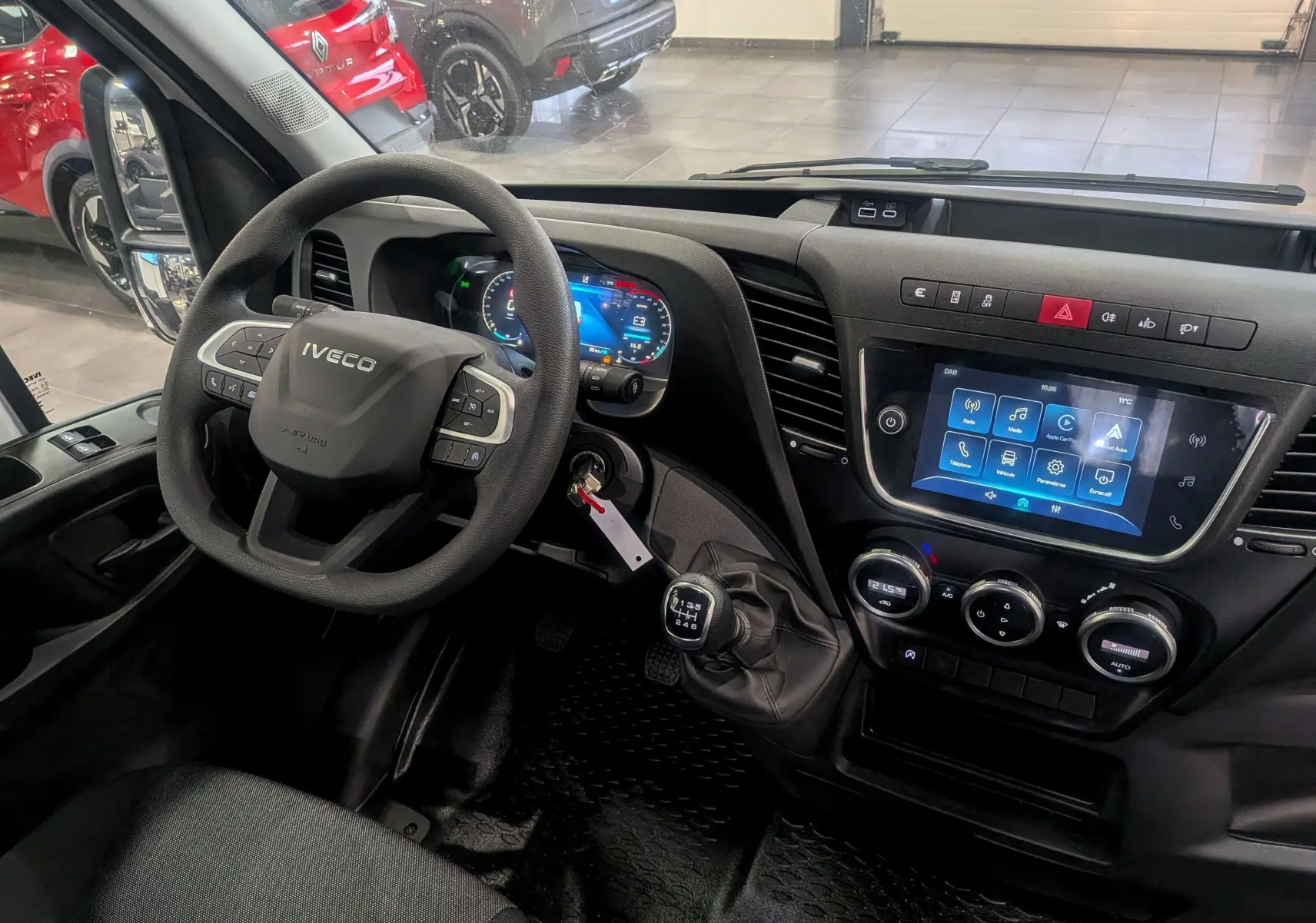 Vue intérieure côté conducteur du tableau de bord de l'Iveco Daily Fourgon blanc 2025 avec volant multifonction et écran tactile.