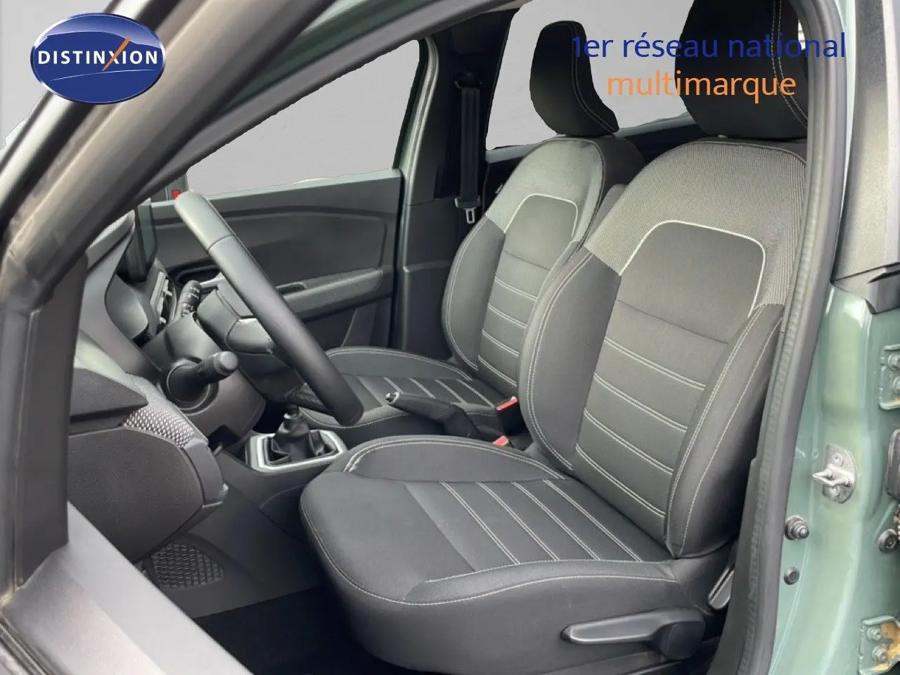 Vue intérieure côté conducteur du Dacia Jogger 2025 kaki lichen, montrant les sièges avant en tissu noir et gris.
