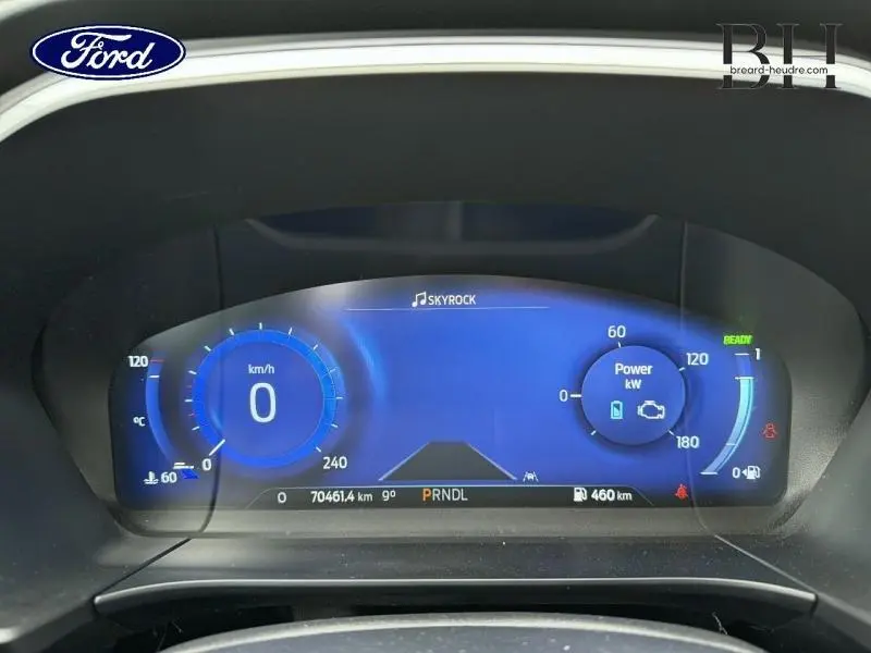 Tableau de bord numérique du Ford Kuga 2023 affichant la vitesse, la puissance et l'autonomie, avec éclairage bleu.