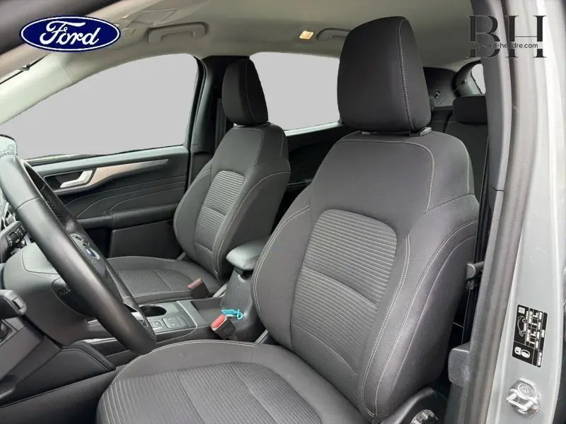 Vue intérieure côté conducteur du Ford Kuga gris Solar, mettant en valeur les sièges avant sport en tissu noir.