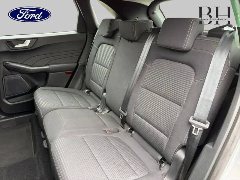 Vue intérieure côté droit des sièges arrière gris foncé du Ford Kuga 2023 avec ceintures de sécurité et porte arrière visible.