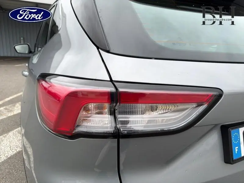 Gros plan sur le feu arrière droit du Ford Kuga gris Solar métallisé, soulignant les lignes modernes du SUV hybride 2023.