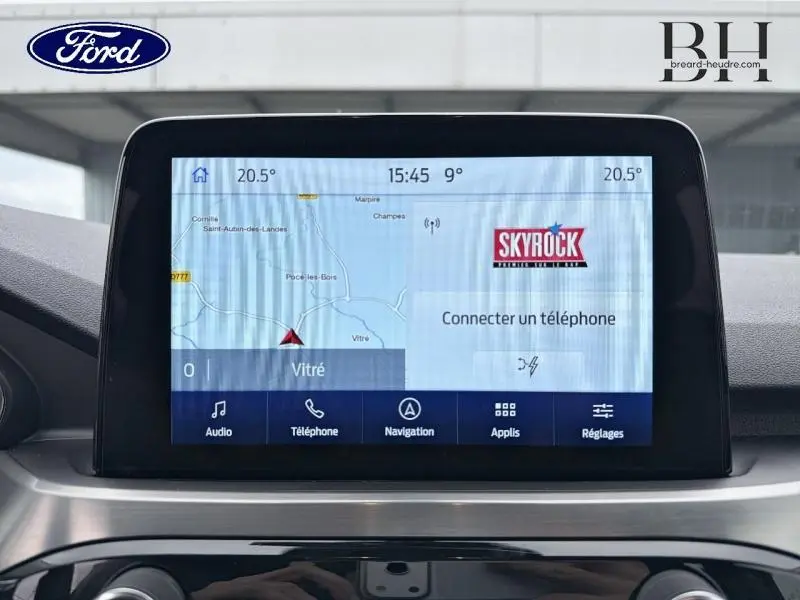 Écran tactile central du Ford Kuga 2023 affichant la navigation et la radio Skyrock, intérieur gris.