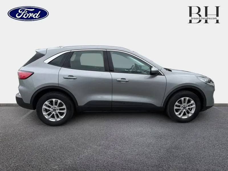 Ford Kuga 2023 gris Solar métallisée vu de profil côté gauche, avec jantes alu et barres de toit noires.