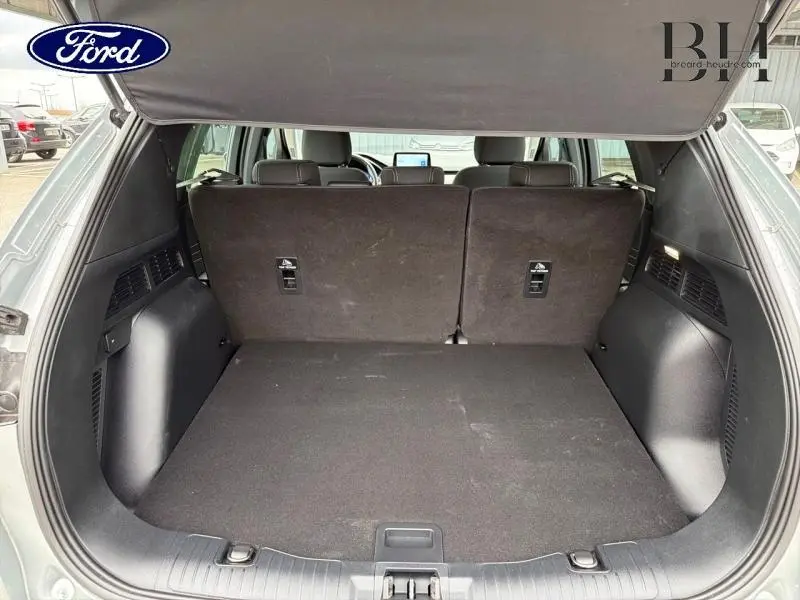 Coffre ouvert du Ford Kuga gris Solar Métallisé, vue arrière montrant la banquette arrière en position verticale.