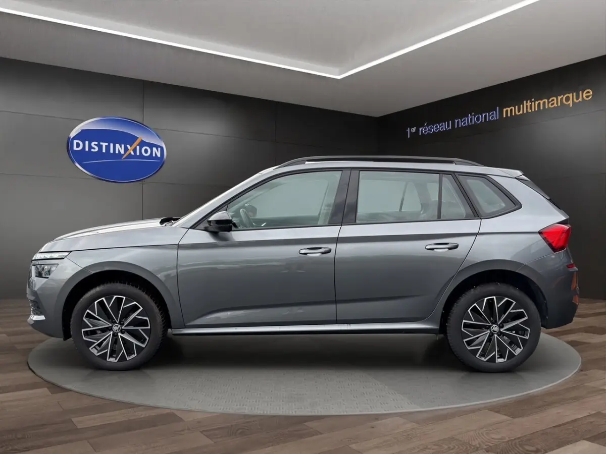 Vue 3/4 avant droite d'une Skoda Kamiq gris foncé avec jantes bi-ton et calandre noire brillante.