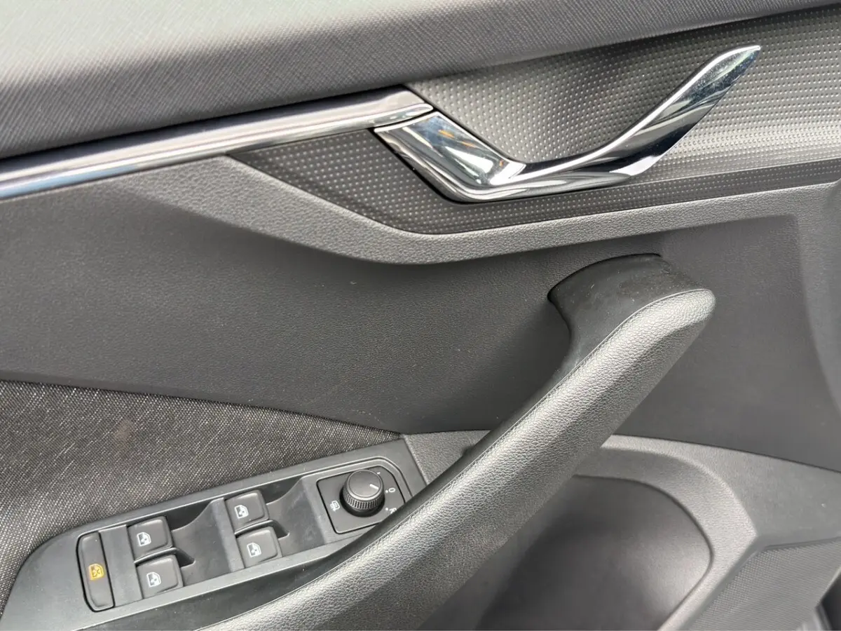 Vue intérieure côté conducteur du Skoda Kamiq 2023 gris foncé, avec sièges tissu bicolore et tableau de bord clair.