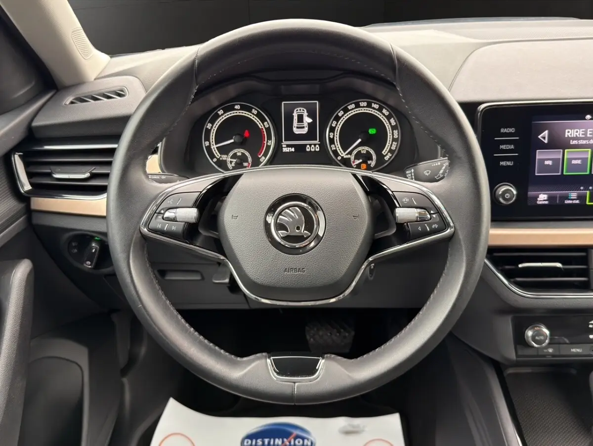 Vue intérieure avant du Skoda Kamiq 2023, tableau de bord clair avec écran tactile et sièges bi-ton gris foncé et clair.