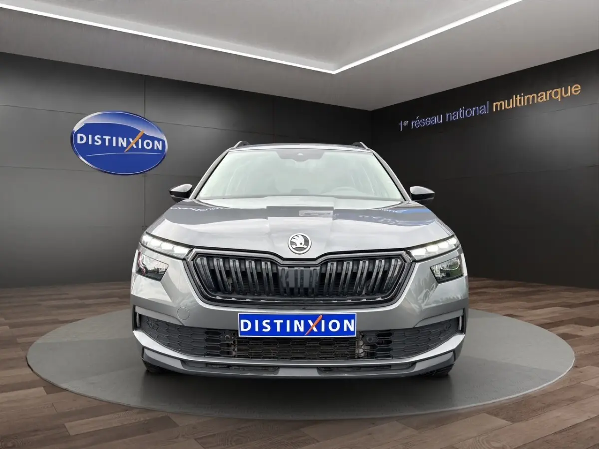 Vue 3/4 avant droite d'un Skoda Kamiq gris foncé avec jantes bi-ton et calandre noire en showroom.