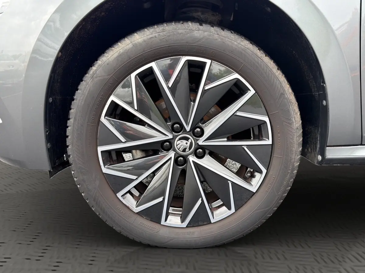 Vue avant d'un Skoda Kamiq gris foncé avec calandre noire et logo centré, présenté en showroom Distinxion.