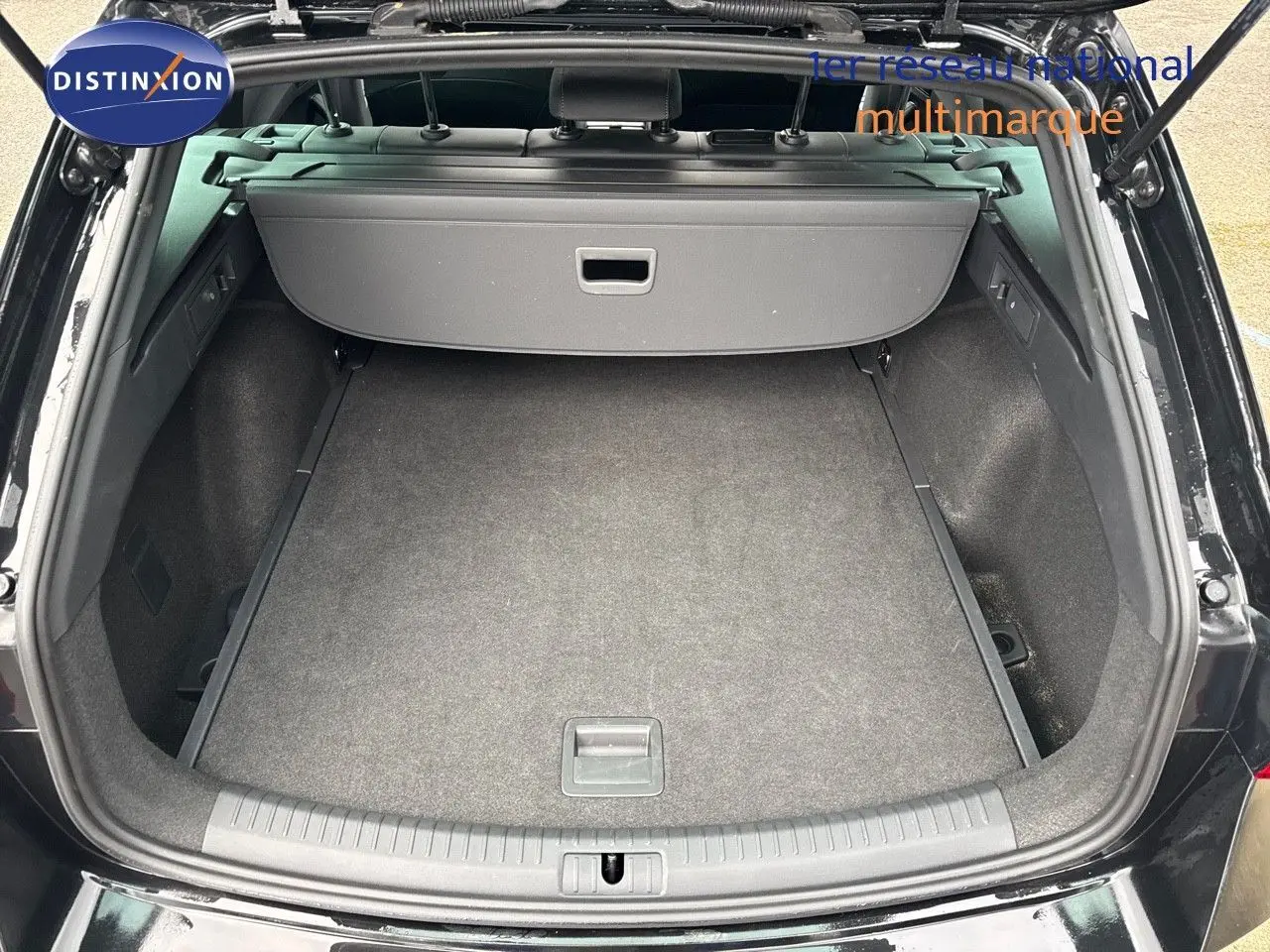 Coffre ouvert d'une CUPRA LEON ST noir midnight metal, vue arrière montrant l'espace de chargement vide et la plage arrière.