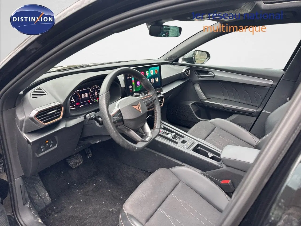 Intérieur avant de la CUPRA LEON ST 2024 noir midnight metal, tableau de bord numérique et écran tactile central visible.