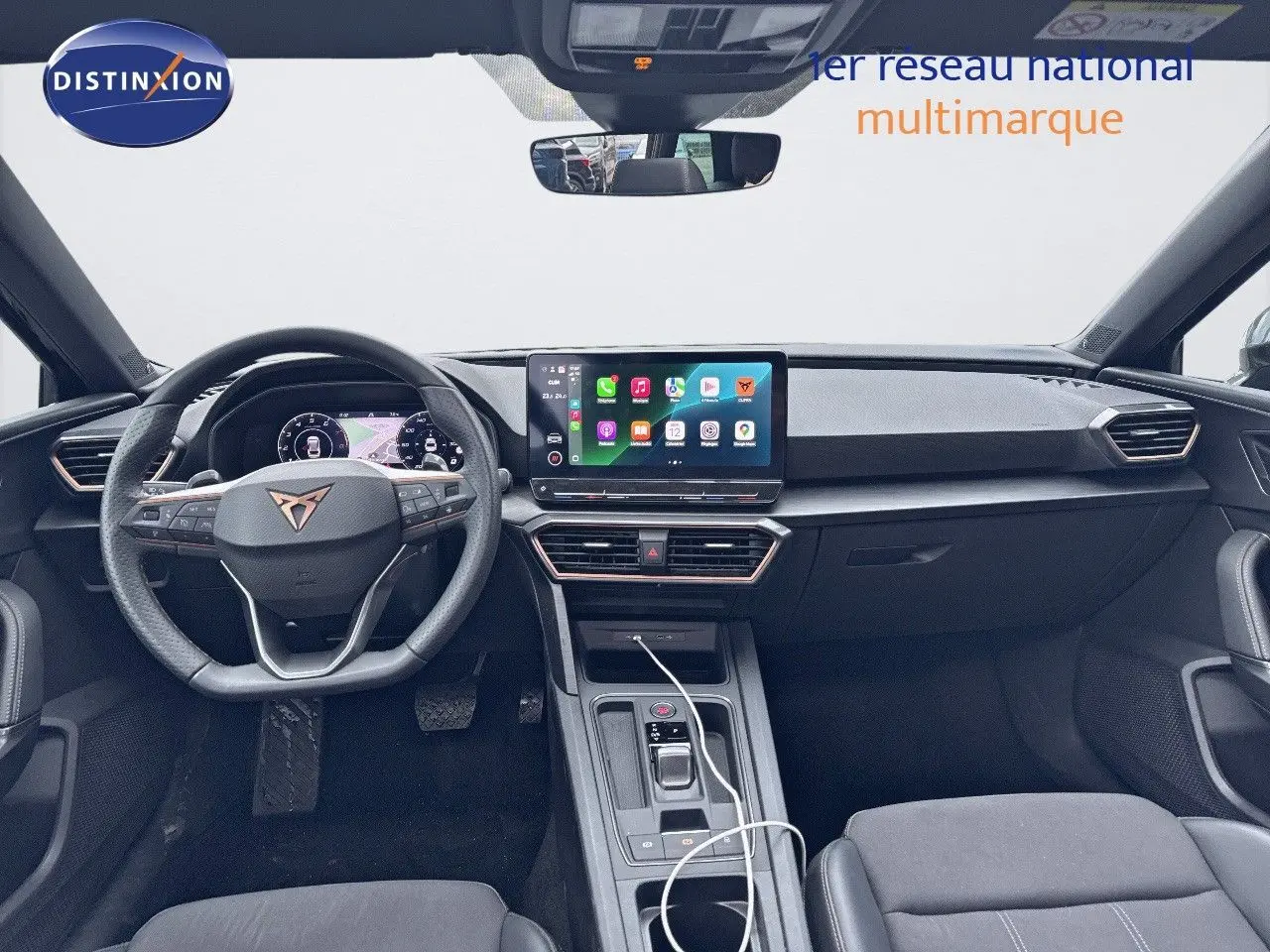 Vue intérieure frontale du tableau de bord noir du CUPRA LEON ST 2024 avec écran tactile et volant multifonction.