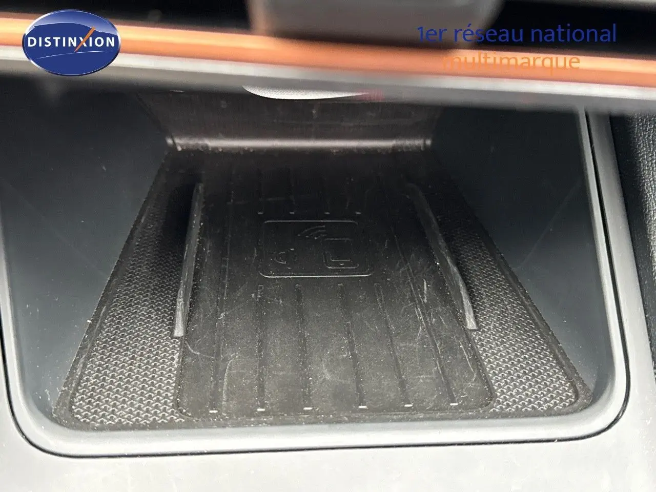 Gros plan sur le chargeur sans fil noir intégré dans la console centrale d'une CUPRA LEON ST 2024.