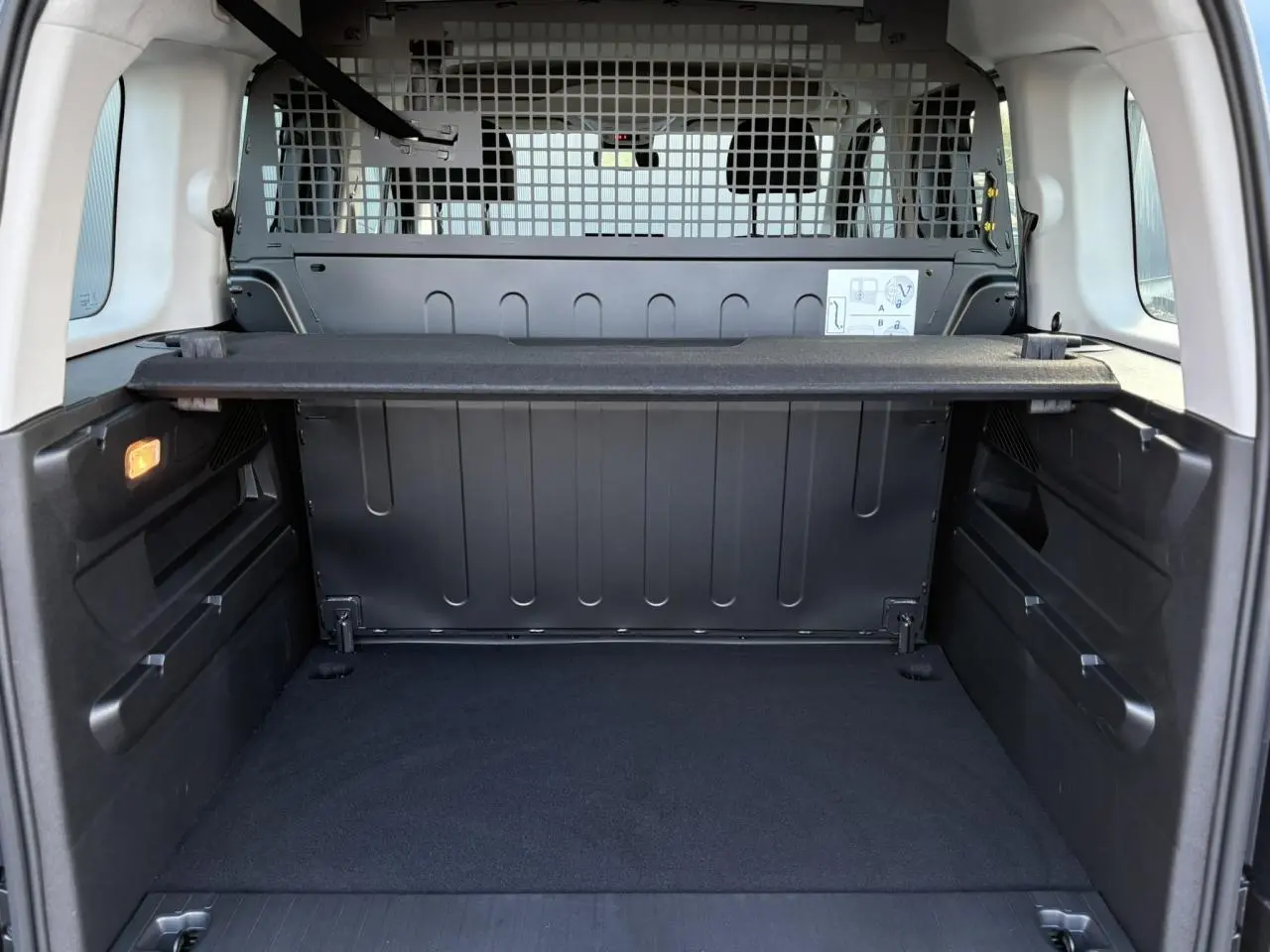 Vue intérieure du coffre du Citroën Berlingo Multispace bleu 2025, avec séparation grillagée et tablette de rangement.