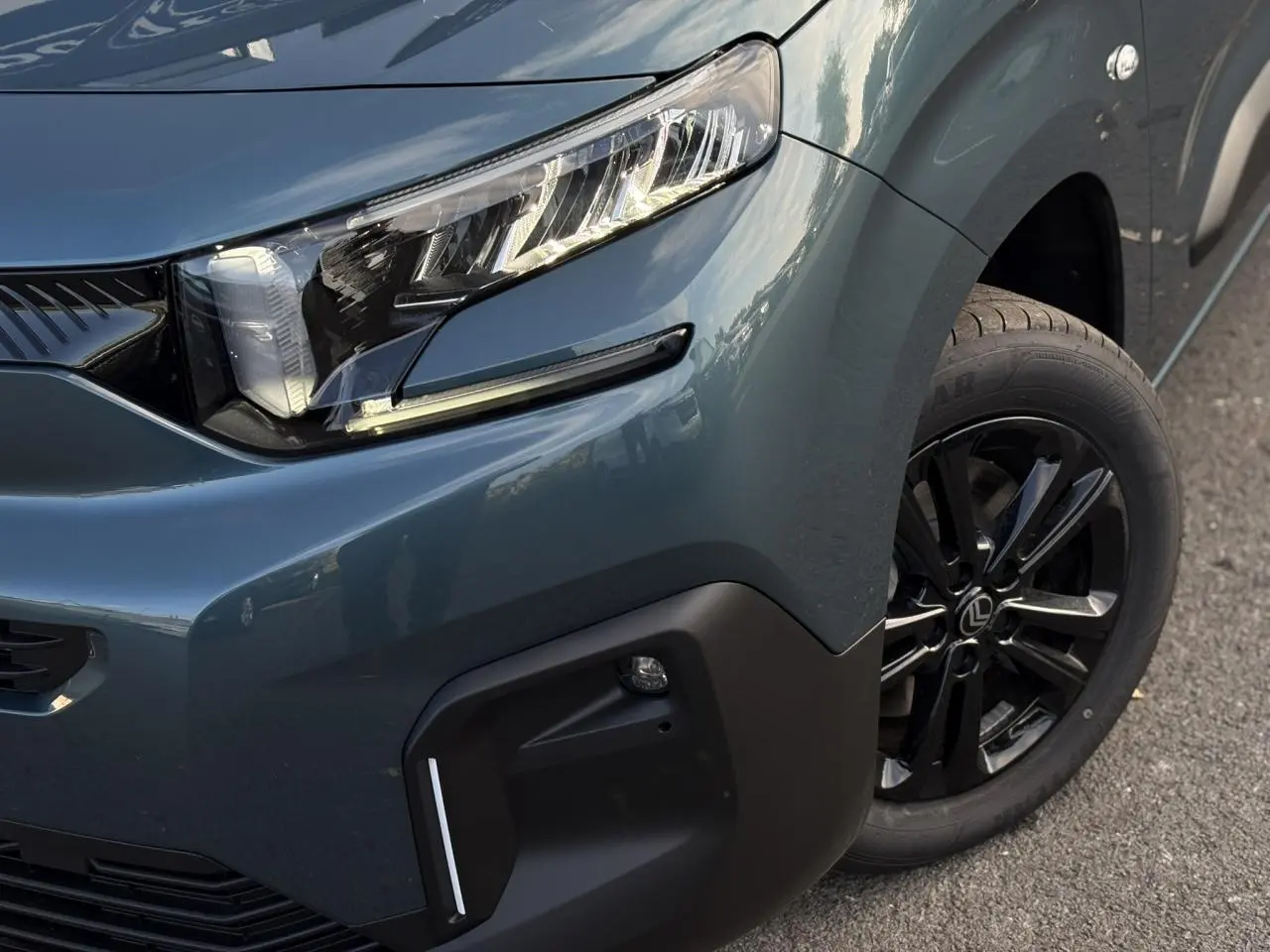 Gros plan sur l'avant droit bleu métallisé du Citroën Berlingo Multispace avec phare LED et jante alliage noire.