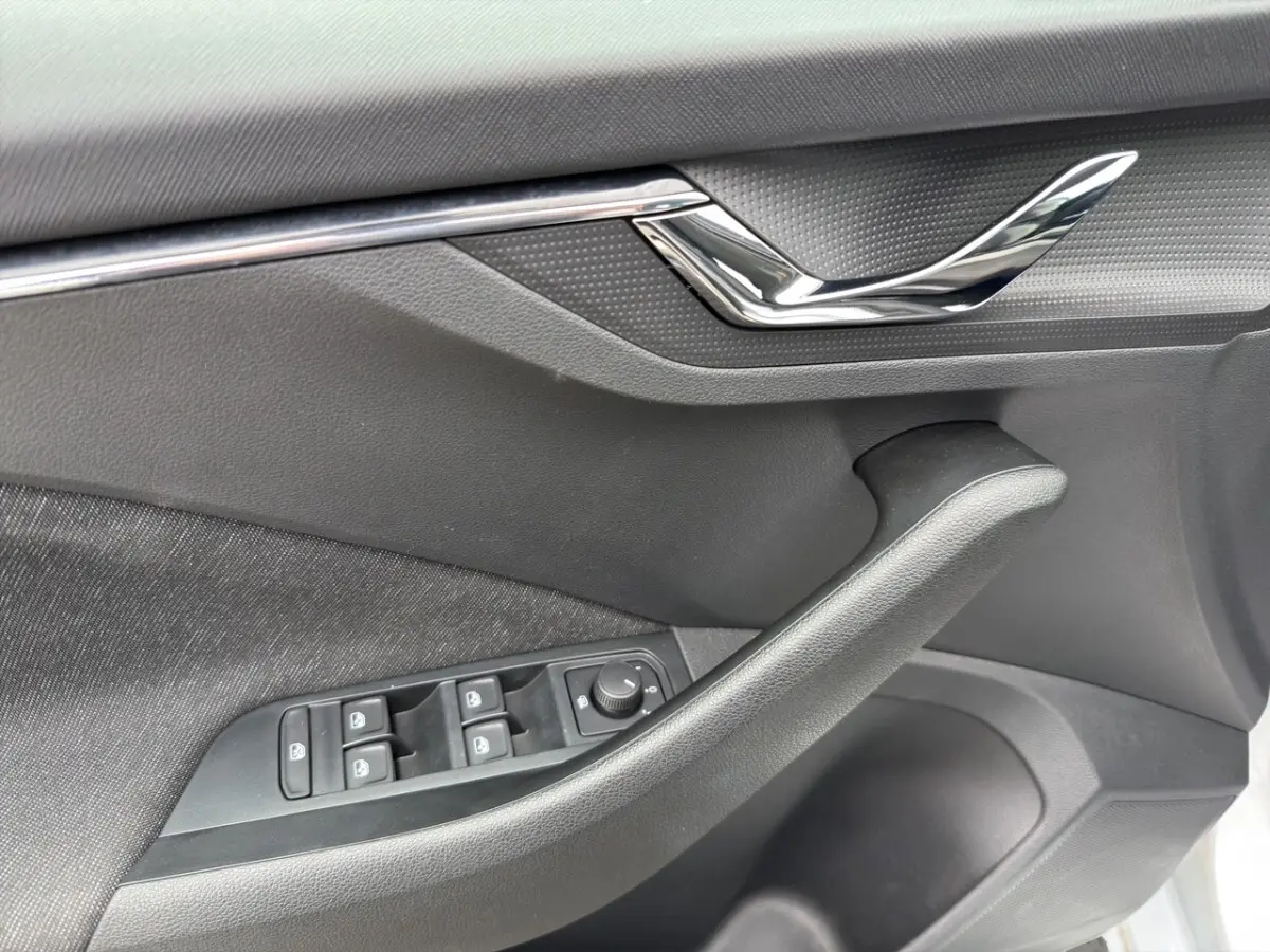 Vue intérieure côté conducteur du Skoda Kamiq 2023 gris clair, mettant en valeur les sièges tissu bicolores et le tableau de bord moderne.