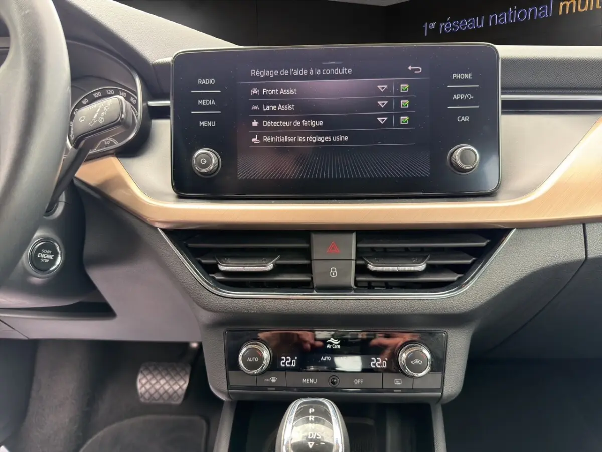 Vue intérieure côté passager du Skoda Kamiq 2023, écran tactile affichant la caméra de recul et détails bois clair.