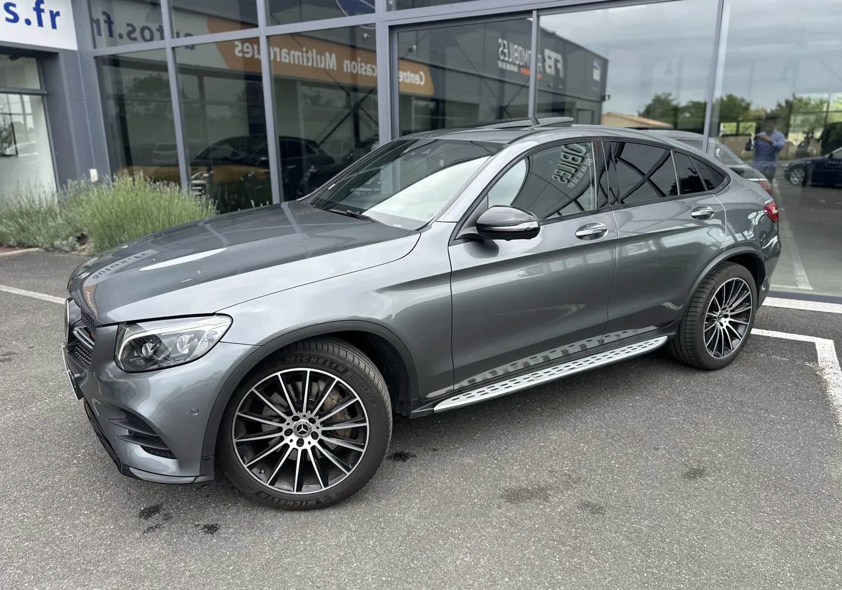 Mercedes GLC Coupé 250 D gris foncé vu de 3/4 avant droit avec jantes alliage et marchepieds métalliques.