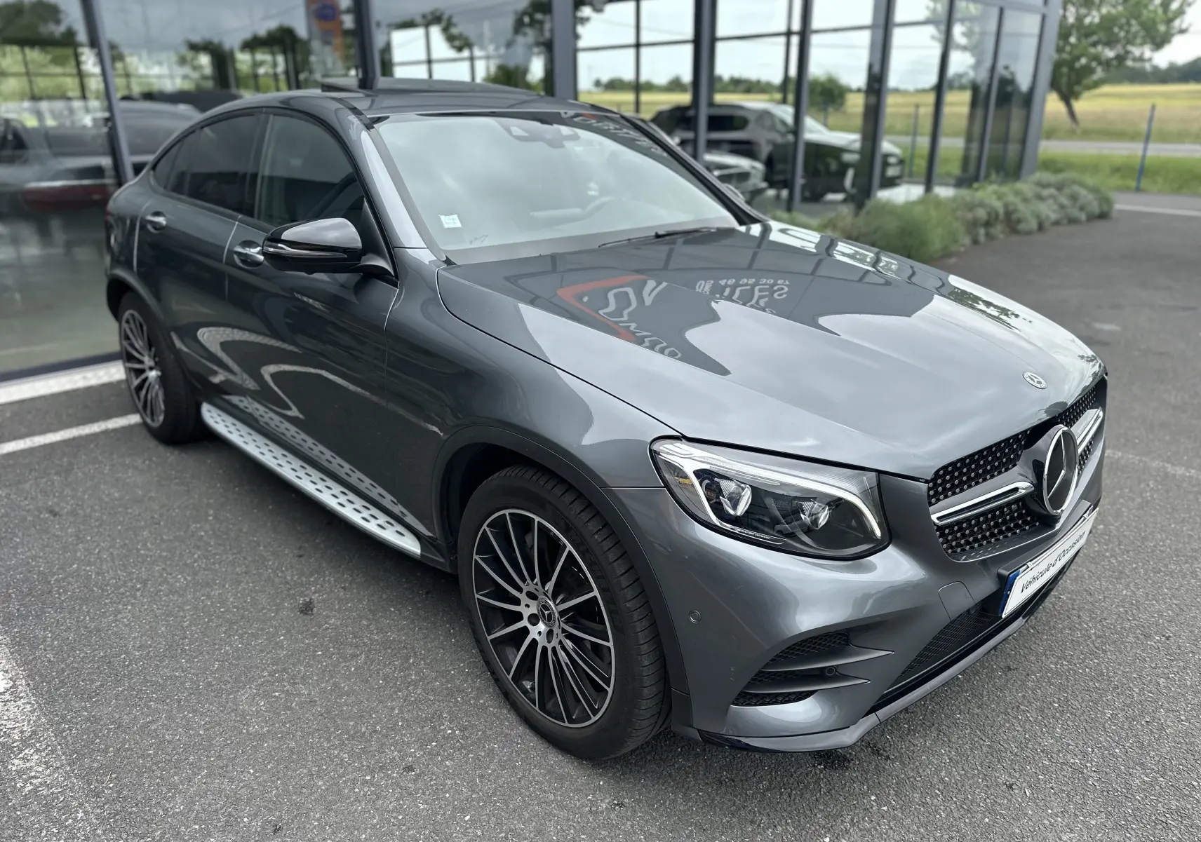 Mercedes GLC Coupé 250 D gris foncé en 3/4 avant droit, avec jantes alliage et marchepieds latéraux visibles.