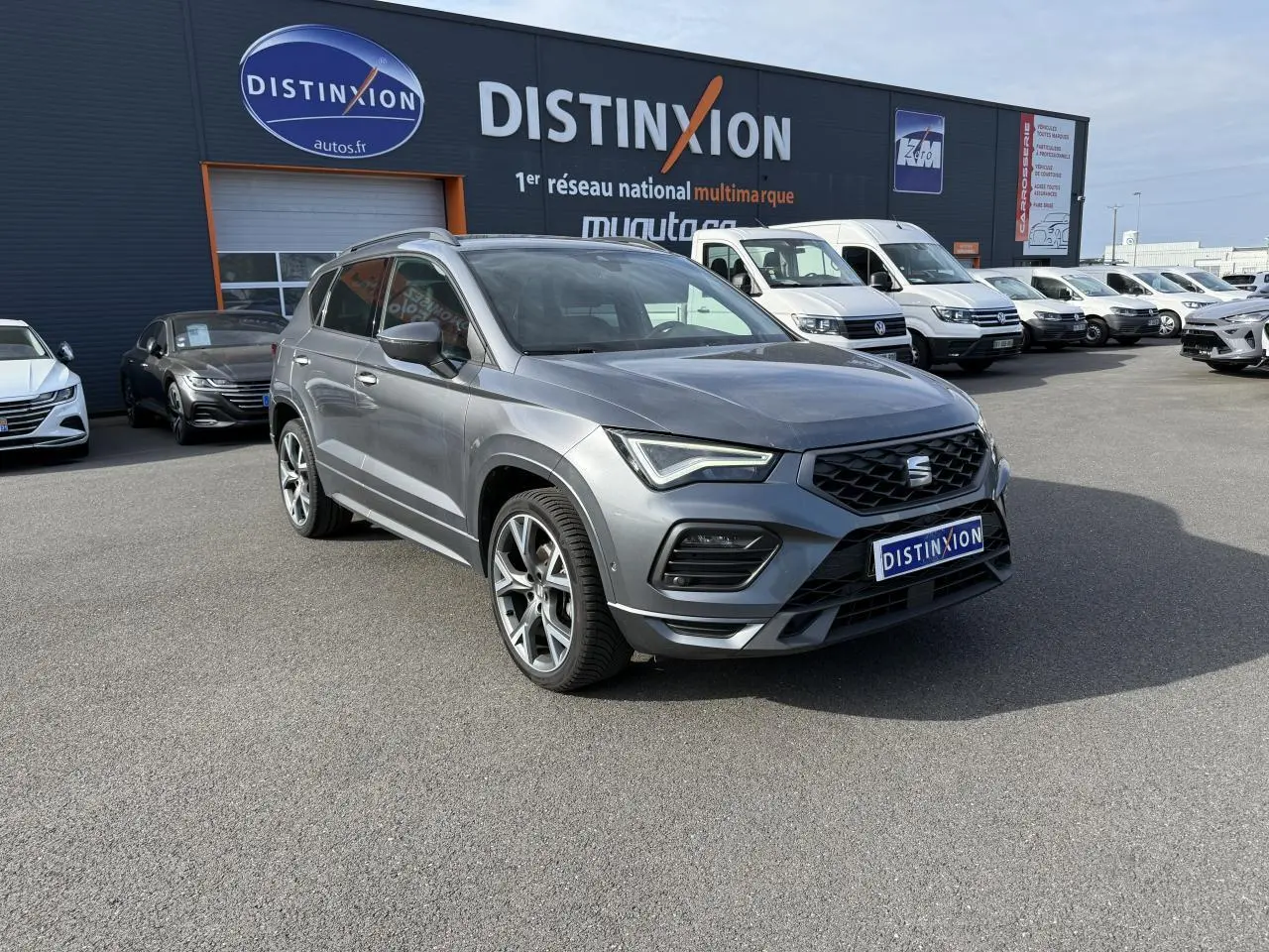 SEAT Ateca gris graphite en 3/4 avant droit avec jantes alu 19 pouces, stationné devant un concessionnaire Distinxion.
