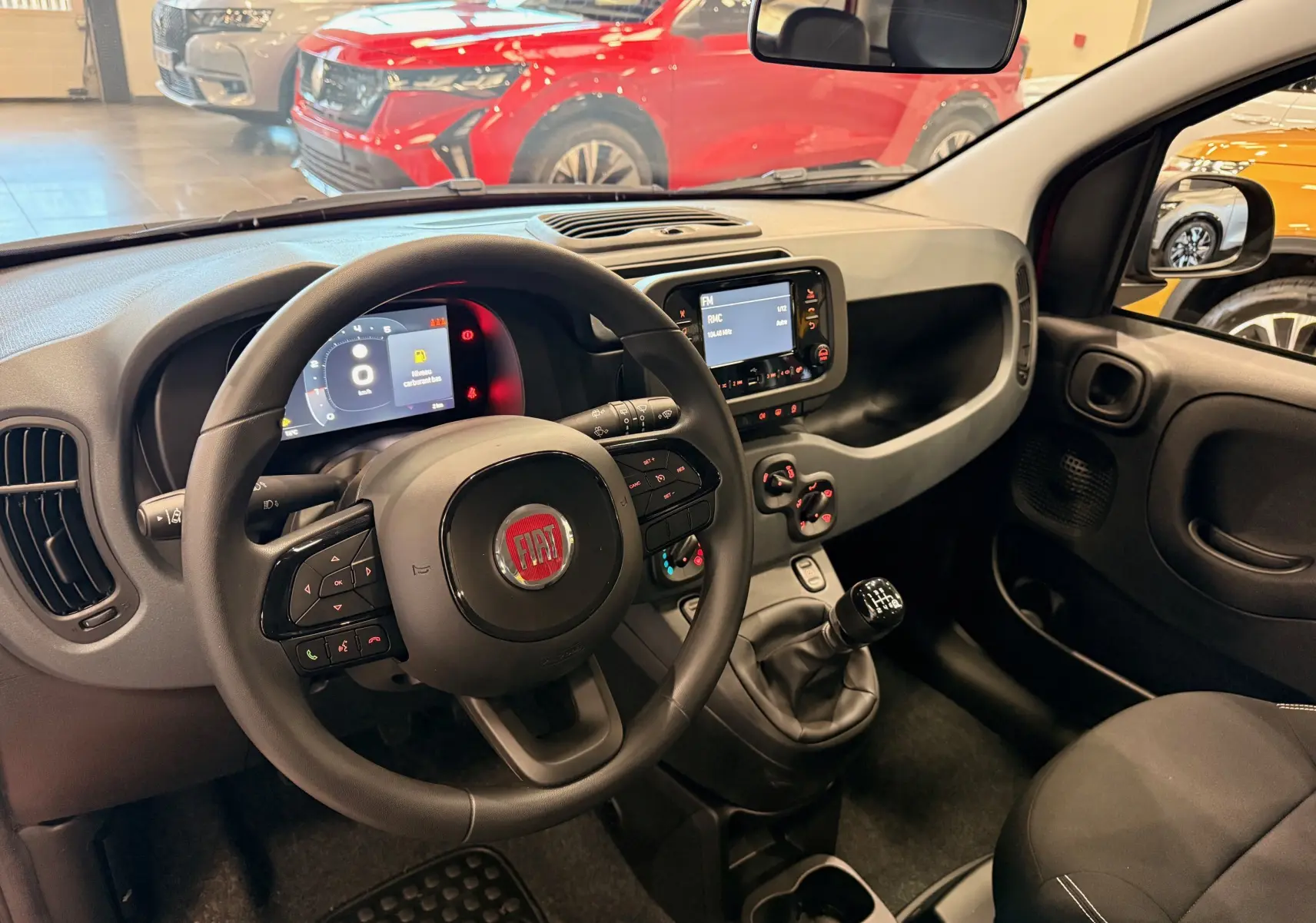 Vue intérieure côté conducteur de la Fiat Panda 1.0 Hybrid 2025, volant multifonction et tableau de bord numérique.