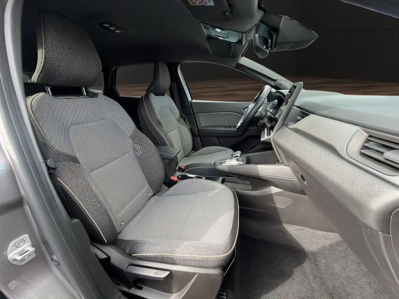 Vue intérieure côté droit de la Renault Symbioz gris clair, montrant les sièges avant et le tableau de bord moderne.