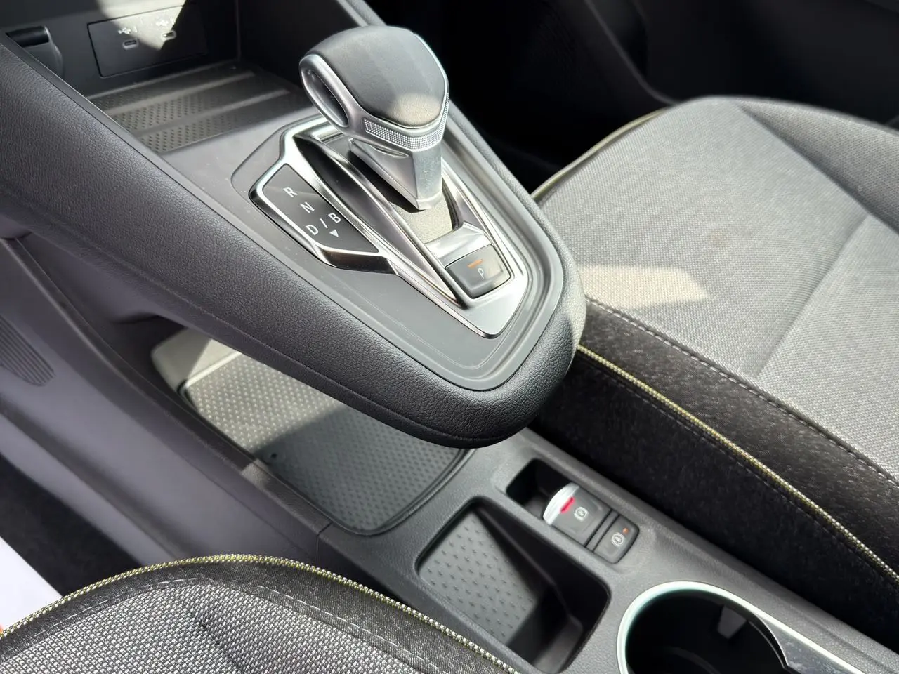 Gros plan sur la console centrale et levier de vitesse automatique du Renault SYMBIOZ gris clair, avec sièges tissu gris.